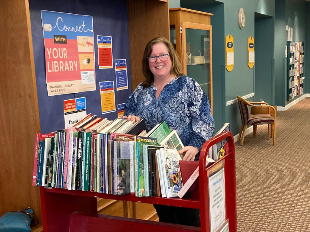 volunteer stands at book sale cart