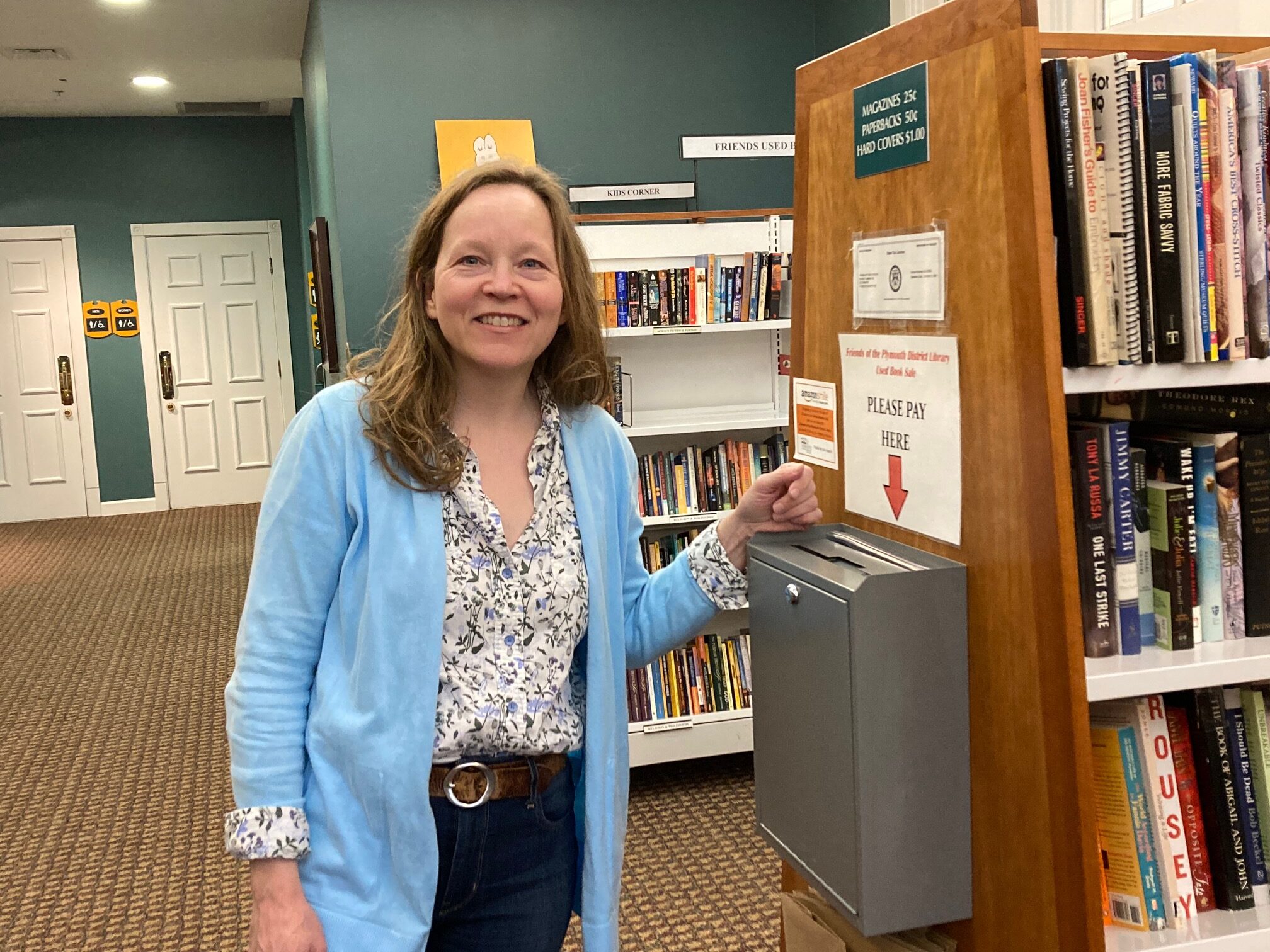 Friends Board member Ellen Elliot stands by book sale cash box